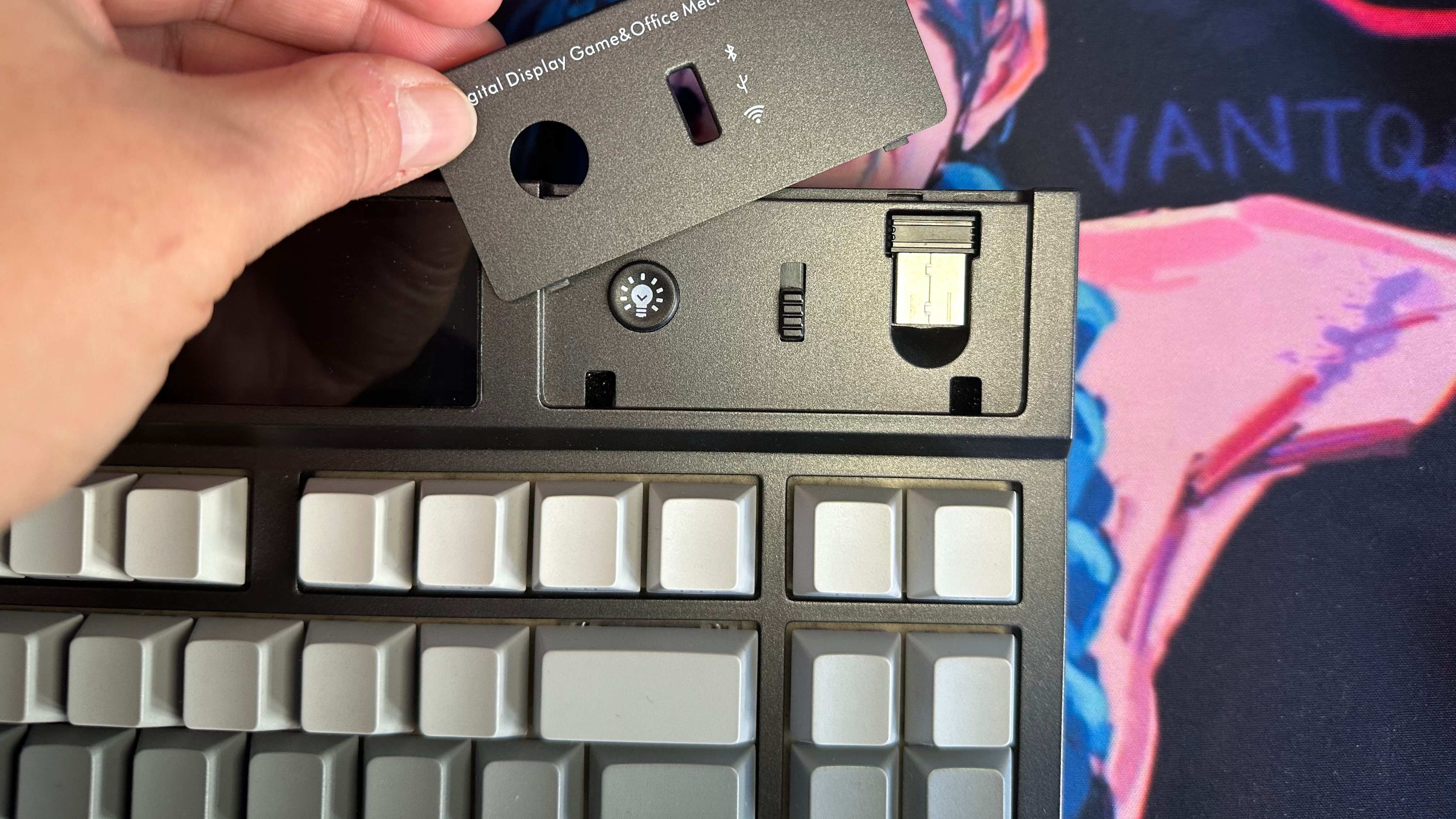 Dettaglio della tastiera EPOMAKER DynaTab 75X con un coperchio removibile che nasconde il dongle USB e i controlli di connessione.