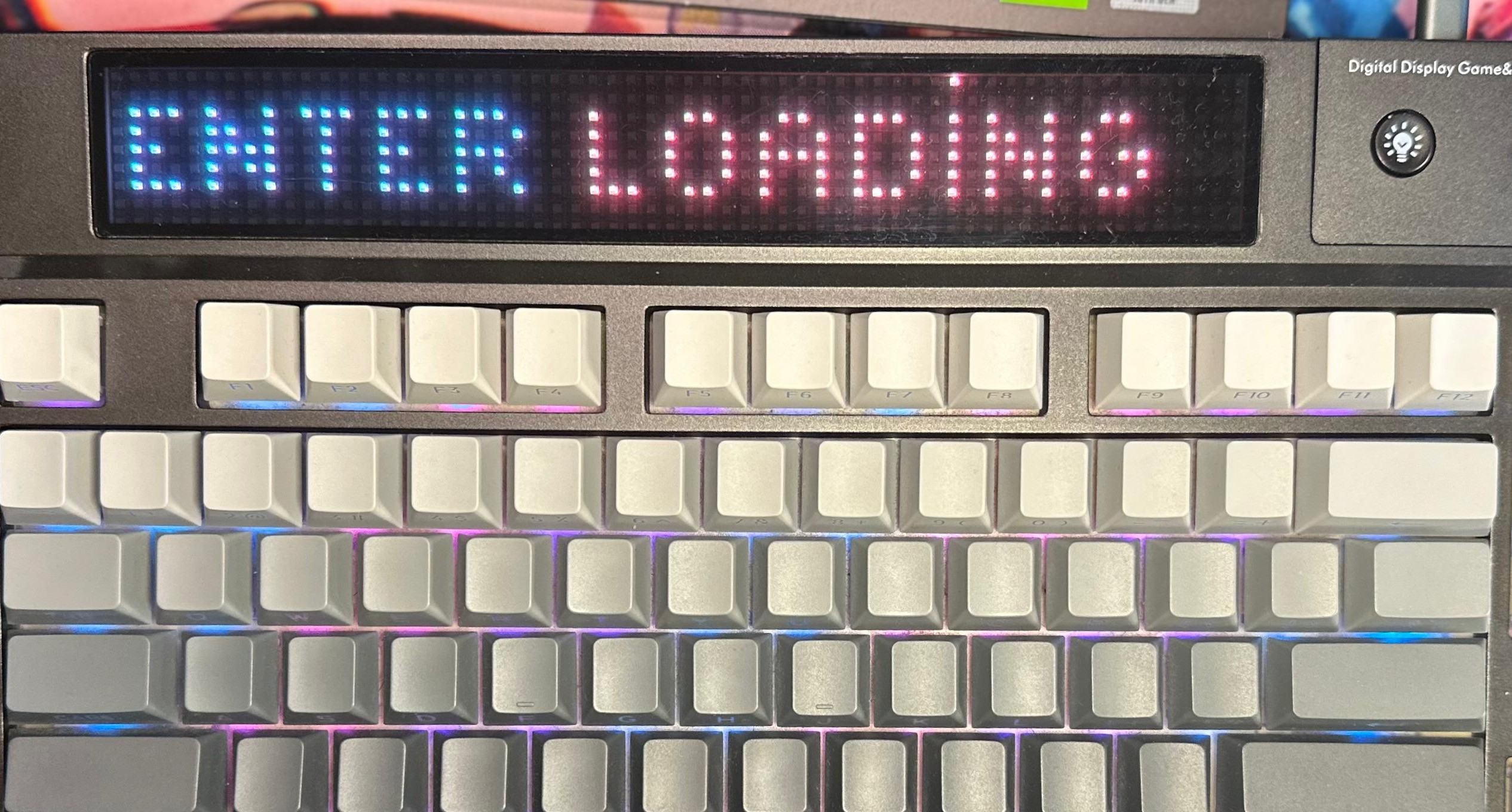 Vista ravvicinata della tastiera meccanica EPOMAKER DynaTab 75X, evidenziando il display Matrix sopra i tasti funzione che mostra la scritta "ENTER LOADING".